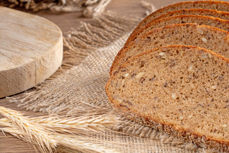 Slices of fresh rye bread with grains lie on a burlap napkin, close-up rustic style.
