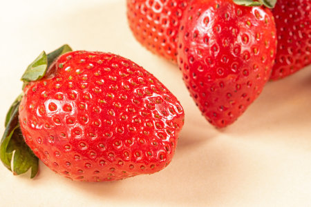 Intimate close-up view of vibrant ripe strawberries on a dark background. Ripe red strawberries arranged in a close-up composition, highlighting their vibrant color and juiciness.の写真素材