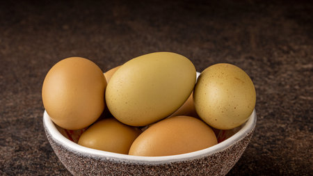 Close-up shot of a collection of rare chicken eggs with unique grey-green shells, highlighting the...