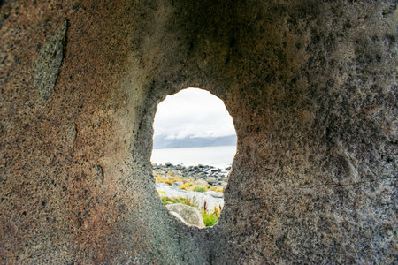 A bizarre boulder with a hole on the sea coast of Norwayの写真素材