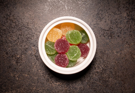 Saucer with colorful marmalade balls on black kitchen table, top view, close-upの写真素材