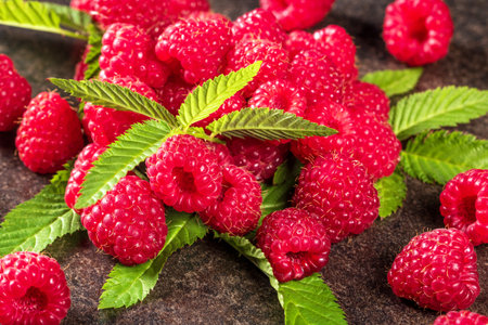 A captivating composition showing fresh, juicy red raspberries adorned with vibrant green leaves on...