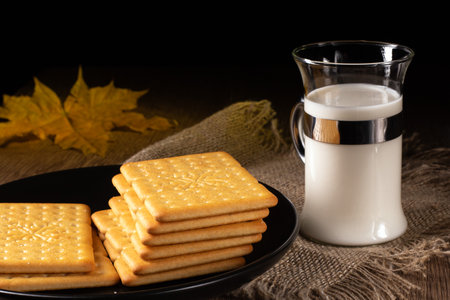 An appealing setup of a glass of milk and a bowl of salty crackers resting on a kitchen table, illustrating a relaxing moment perfect for a snack or light meal whenever you need a break.の写真素材