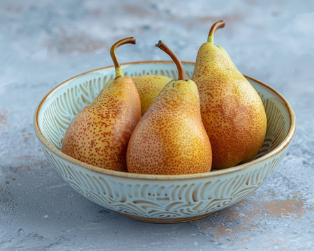 Three ripe white chinese pears in a ceramic bowl on a textured light blue surface with natural lightの素材