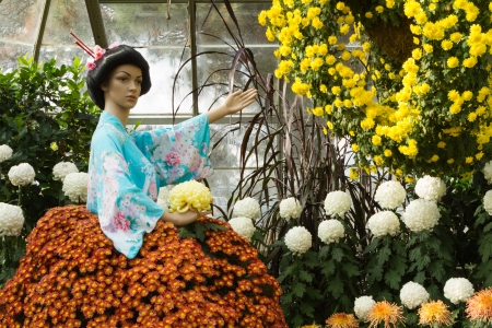 Asian woman mannequin dressed in aqua floral kimono top and a skirt made of real flowers in a gardenの写真素材
