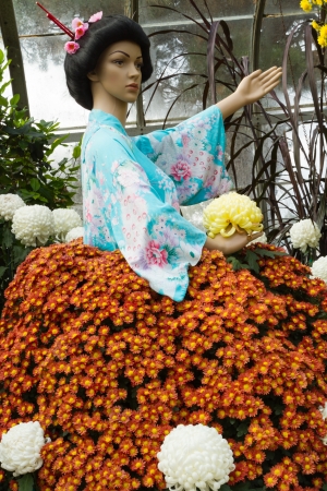 Asian woman mannequin dressed in aqua floral kimono top and a skirt made of real flowers in a gardenの写真素材