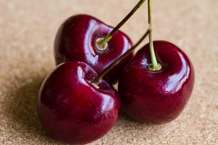 Closeup of three red cherries on stalksの写真素材