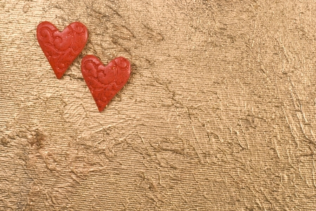 Two red hearts on the up left corner on a golden surface. Space for your text.の写真素材