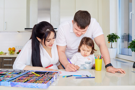 Smiling family drawing together in kitchen at homeの写真素材