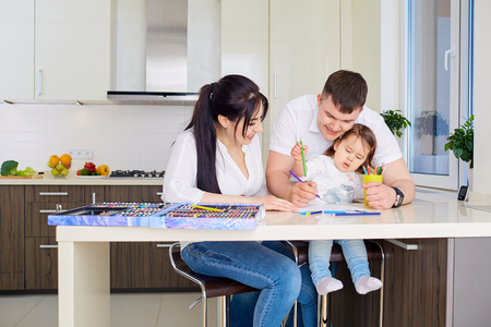 Smiling family drawing together in kitchen at homeの写真素材