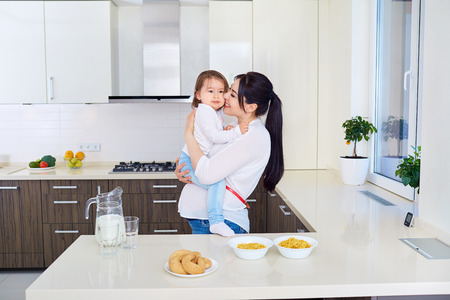 Pregnant mother playing with toddler daughter on the kitchenの写真素材