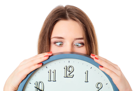 Woman holding clock  with wondering eyes foolishly.の写真素材