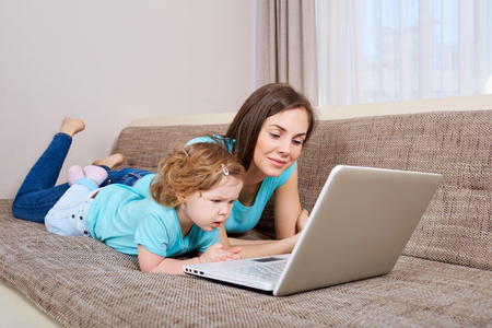 Mother and her daughter looking at laptop at homeの写真素材