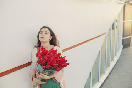 Young blond woman with a bouquet of red tulipsの写真素材