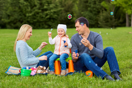 Family playing with bubbles outdoors.の写真素材