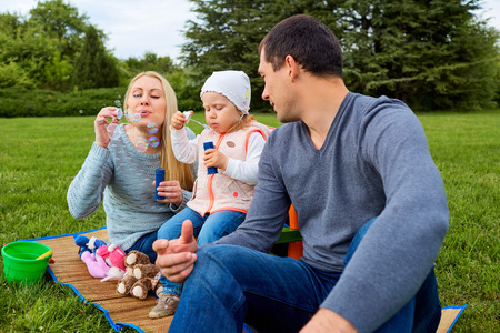Family enjoying their time with  soap bubbles. Day off with soap bubbles in the park.の写真素材