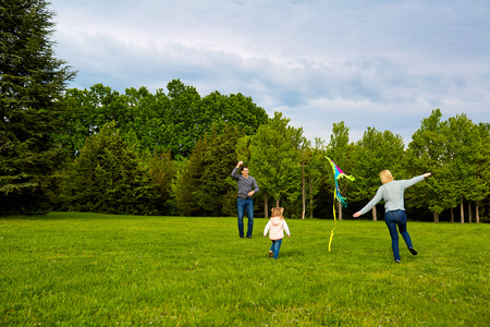 Happy young family with flying a kite in the park.の写真素材
