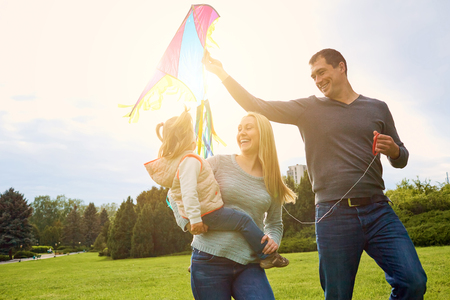 Happy family with colorful kite on nature. Sunlight.の写真素材
