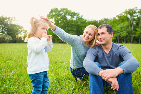 Happy mom and dads and daughter on the grass in the park. Family, smile, joy.の写真素材
