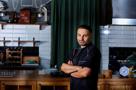 Chef portrait in black uniform in the restaurant.