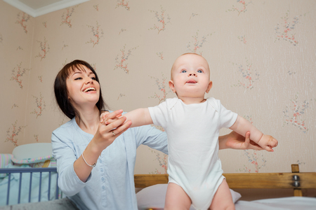 Mum learns the baby to go on the bed. Happy and smile.の写真素材