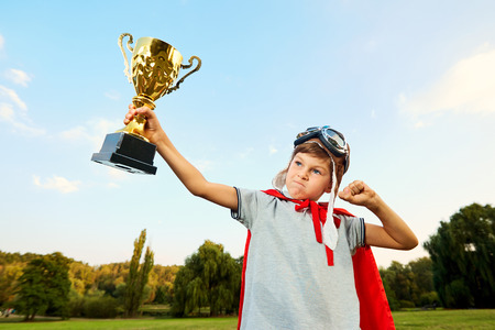 Superhero boy with a championship trophy in hands on nature shows its muscles and strength.の写真素材