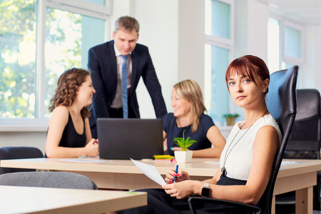 Portrait of  business woman in the office in a chair on the background of working business partners.の写真素材