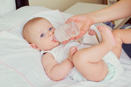 Mother bottle feeding her baby.The care, the education of childrenの写真素材