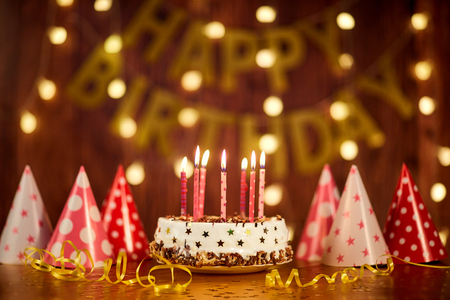 Happy birthday cake with candles on the background of garlands and letters.の写真素材