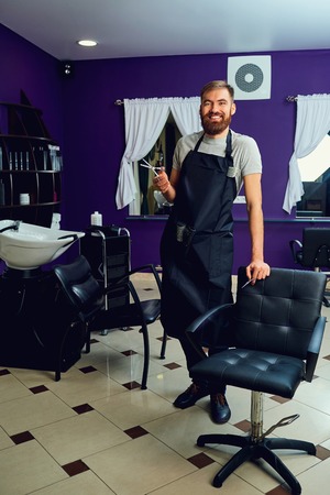Hairdresser man with a beard  scissors in his hands at hairdresser.の写真素材