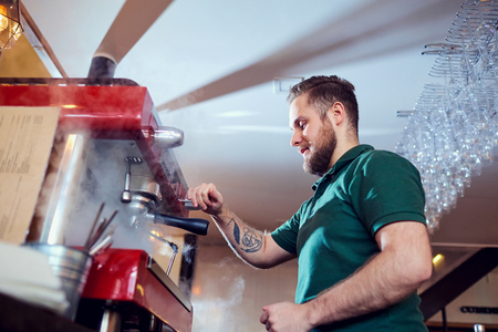 The barman, barista, makes a hot coffee drink at  bar counter in  workplace.の写真素材