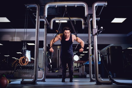 A man is doing exercises on  simulator in the gym.