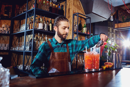 The bartender laughs making a cocktail at the bar.の写真素材