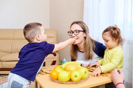 The son feeds his mother mom apple in room at table.の写真素材