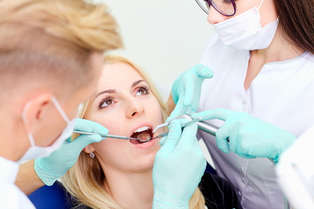 Two dentists treat their teeth to  visitor in dental office.の写真素材