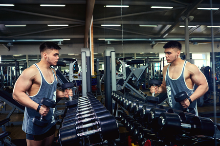 Male athlete with dumbbells in the gym sport club.の写真素材