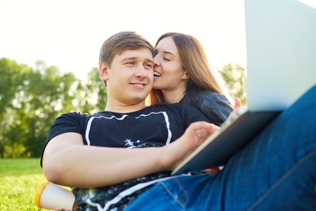 A loving couple with  laptop in the park at sunset.の写真素材