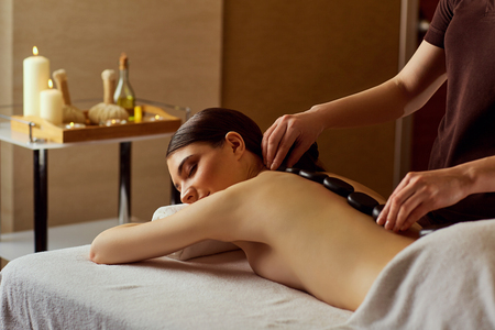 Massage stones on back of a woman at the spa salon.の写真素材