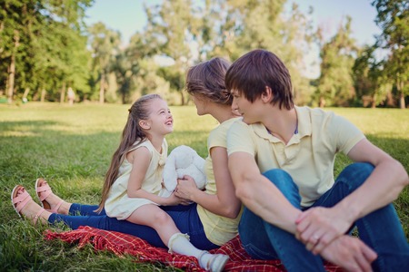 Happy family playing in the park sitting on grass in summer.の写真素材