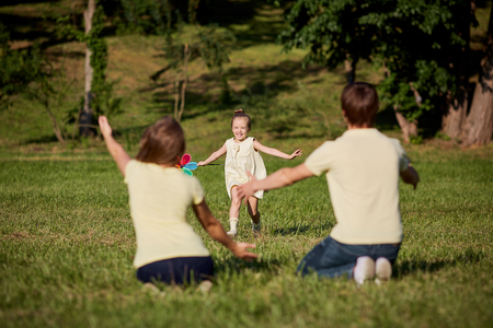 Happy family playing in the park sitting on grass in summer.の写真素材