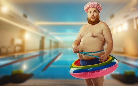 Fat funny man in the inflatable circle in the pool.の写真素材
