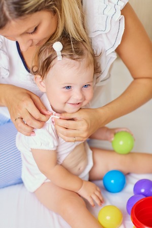 Mom mother dresses her baby child. Parental care.の写真素材