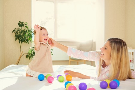 Mom plays with the baby in the room indoors.の写真素材