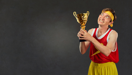 A thin, thin, thin guy with a champions cup in his hands. Comedy humor in a sports champion.の写真素材