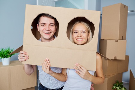 Funny couple with a box on the head in a new house. The concept of housewarming.の写真素材