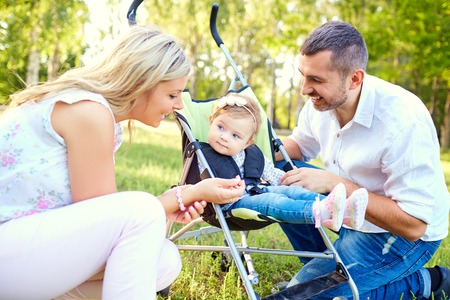 Happy family playing with a baby in a stroller in the park autumn summer.の写真素材