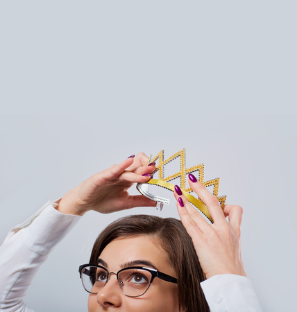 A businesswoman is holding a crown over his head.の写真素材