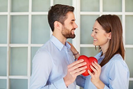 A loving couple with a red heart laugh. Valentines Day.の写真素材