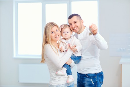 A happy family moves to a new apartment. Mother, father and child with boxes in the room of the new...