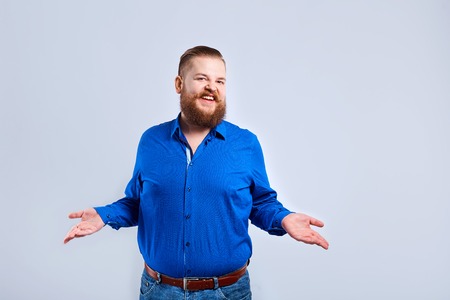 A fat, bearded man on a gray background with a positive expression of emotion.の写真素材